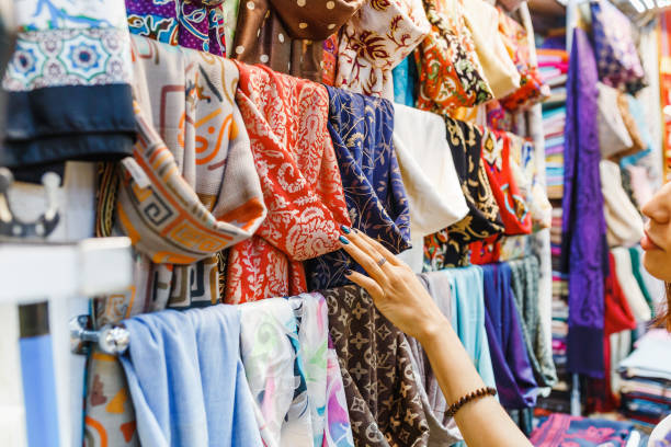 Young Woman Shopping For A New Scarf and choosing colorful fabric in bazar Destinations Desire