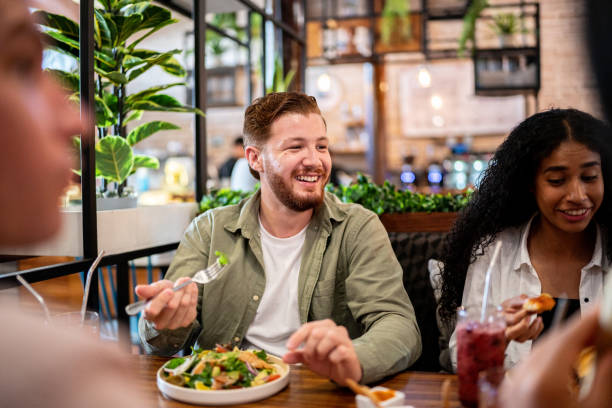 Young man eating with his friends on a restaurant Destinations Desire